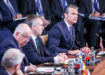 Secretary of War Pete Hegseth speaks while at a table alongside fellow NATO defense ministers.