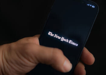 A man holds his phone as he logs into the New York Times mobile app.
