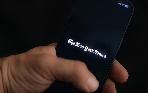 A man holds his phone as he logs into the New York Times mobile app.