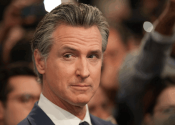 Newsom stands in an audience, looking to the side.