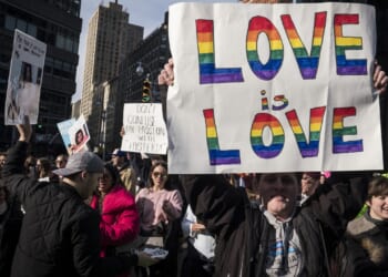 A demonstrater holds up a banner saying "Love Is Love"