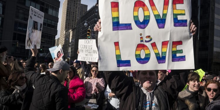 A demonstrater holds up a banner saying "Love Is Love"