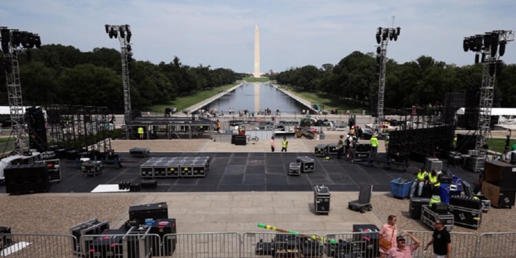 With the Washington Monument and the Reflecting Pool of the National Mall in the background, workers construct a stage for part of the upcoming Ultimate Fighting Championship Freedom 250 event in Washington.