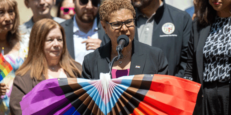 Los Angeles Mayor Karen Bass stands at a podium draped with pride colors.