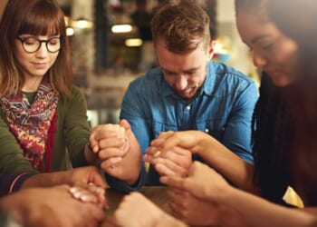 A group of people pray in a circle.