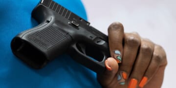 A woman holds a Glock pistol.