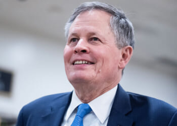 Sen. Steve Daines stands and smiles.