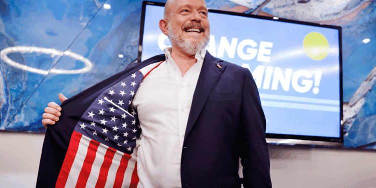 Steve Hilton stands on stage at his election night event smiling.