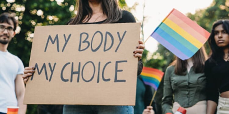 A woman stands with a protest sign with accompanying protesters.