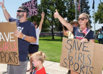 Protesters with signs saying "save girls sports"