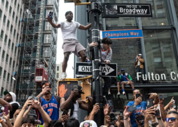 Fans can be seen climbing a lamp post during a parade.
