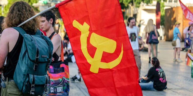 Protesters walk on campus with a communist flag displaying a hammer and sickle on June 19, 2026.