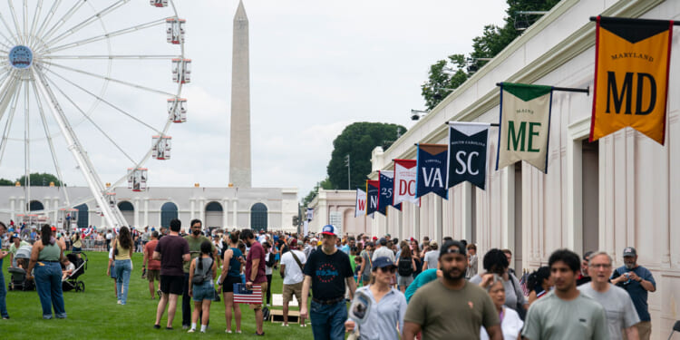 Visitors walk near the 110-foot "Freedom 250" ferris wheel on the third day of the "Great American State Fair" on the National Mall as seen looking toward the Washington Monument on June 27, 2026 in Washington, DC.