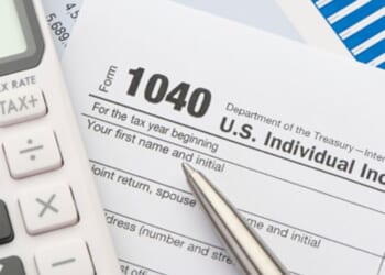 1040 Forms lay on a table alongside a pen and a calculator.