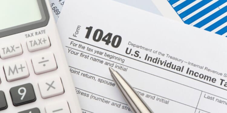 1040 Forms lay on a table alongside a pen and a calculator.