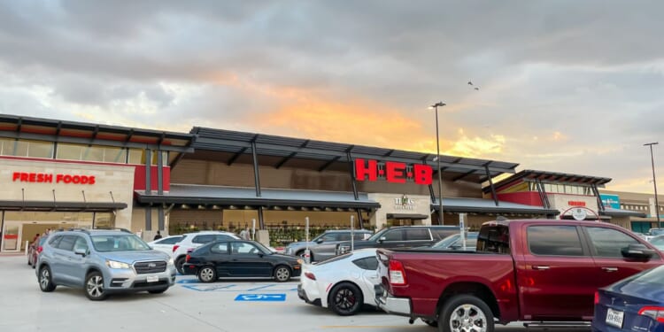 The view from parking lots to the store entrance of a recently opened H-E-B Grocery Company franchise supermarket chain with busy traffic at sunset in Plano, Texas, on July 8, 2023.