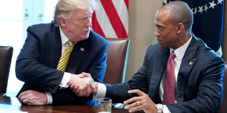 Donald Trump shaking the hand of Department of Housing and Urban Development Secretary Scott Turner. Turner condemned "fraud" in Los Angeles housing.