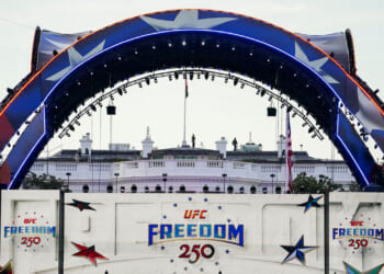 The Claw, part of the area for UFC Freedom 250 arches over the White house and a red, white and blue sign promoting the event.