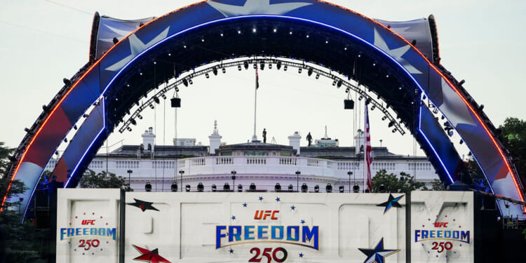 The Claw, part of the area for UFC Freedom 250 arches over the White house and a red, white and blue sign promoting the event.