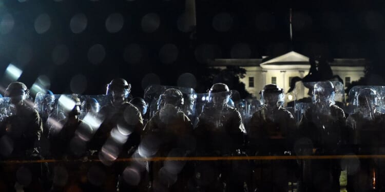 Police officers hold a perimeter behind the metal fence recently erected in front of the White House demonstrators gather to protest the killing of George Floyd on June 2, 2020, in Washington, D.C.