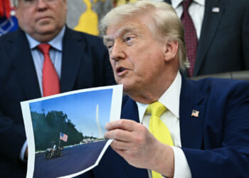 President Donald Trump holds a picture of the newly resurfaced Reflecting Pool on the National Mall as he speaks in the Oval Office of the White House in Washington, DC on June 4, 2026. (Photo by Brendan SMIALOWSKI / AFP via Getty Images)