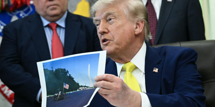 President Donald Trump holds a picture of the newly resurfaced Reflecting Pool on the National Mall as he speaks in the Oval Office of the White House in Washington, DC on June 4, 2026. (Photo by Brendan SMIALOWSKI / AFP via Getty Images)