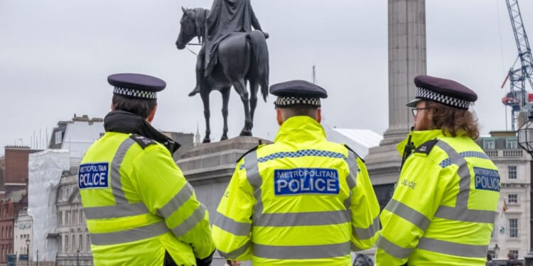 A group of three police officers in Trafalgar Square, Central London, on a chilly, grey day.