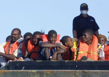U.S. Coast Guard personnel watch over the 188 Haitians picked up Dec. 3, 2001, after their overloaded boat ran aground in 3 feet of water off the South Florida coast about 10 miles south of Miami.