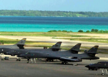 American fighter planes sit on a runway at Diego Garcia base with beautiful blue island waters in background.