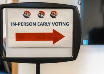 Sign reading "In-Person Early Voting" with a red arrow pointing toward the right.