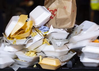 An overflowing bin full of Styrofoam containers is shown.