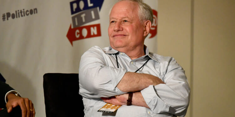 Bill Kristol sits with his arms folded while in a white shirt.