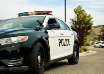 A locked off shot of a police car in a California suburb on a mostly clear day in spring.