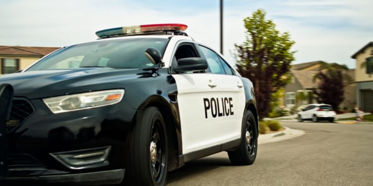 A locked off shot of a police car in a California suburb on a mostly clear day in spring.