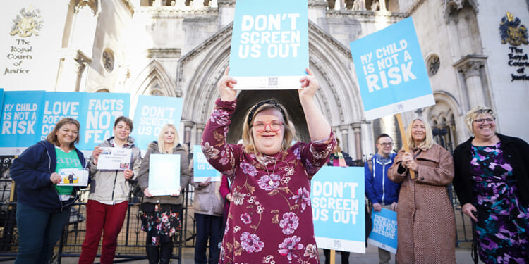 Girl standing with a sign saying, "Don't Screen Us Out."
