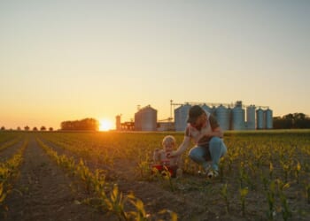 A mother and toddler son playing with a toy tractor.