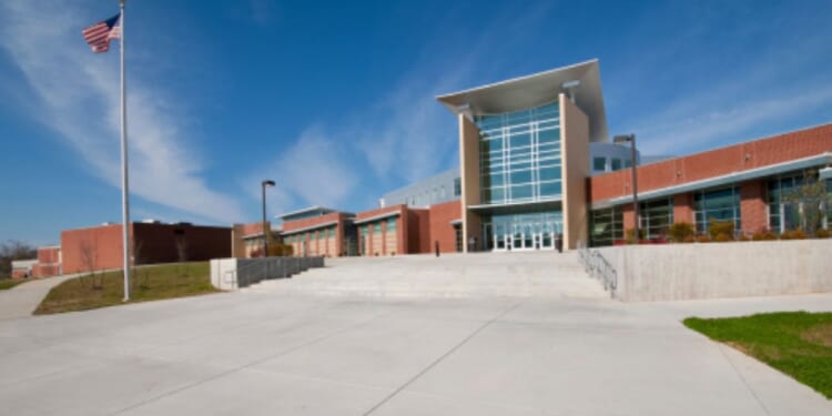 An American school building stands as an American flag waves in the wind.