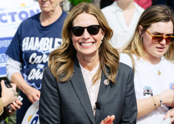 Dr. Amy Acton, Democratic nominee for Ohio's governor, smiles at outdoor an event while she wears sunglasses and a dark suit.