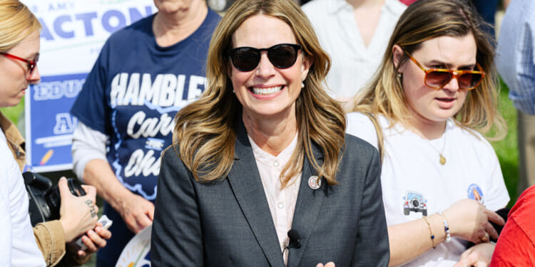 Dr. Amy Acton, Democratic nominee for Ohio's governor, smiles at outdoor an event while she wears sunglasses and a dark suit.
