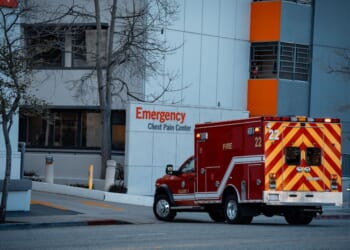 An emergency medical services vehicle is positioned near the entrance of a hospital's emergency department.