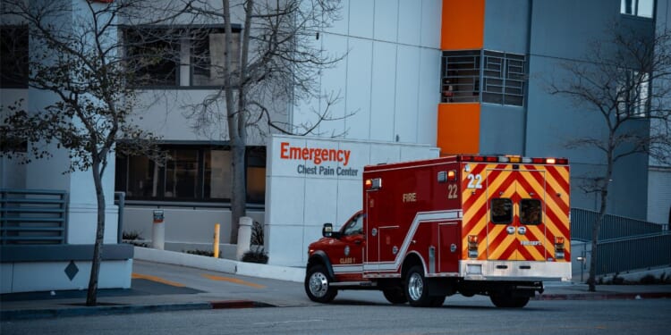 An emergency medical services vehicle is positioned near the entrance of a hospital's emergency department.