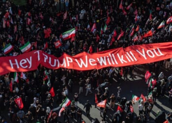 Mourners of the authoritarian Iranian Supreme Leader Ayatollah Ali Khamenei hold up a banner threatening the life of President Donald Trump on July 9, 2026 during a funeral procession for the leader in Mashhad, Iran.