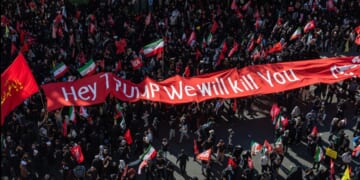 Mourners of the authoritarian Iranian Supreme Leader Ayatollah Ali Khamenei hold up a banner threatening the life of President Donald Trump on July 9, 2026 during a funeral procession for the leader in Mashhad, Iran.