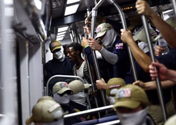 A passenger looks on as members of the white supremacist group Patriot Front ride the Washington Metro on July 4, 2026, in Washington, D.C.