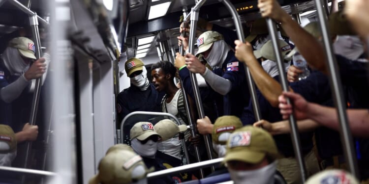 A passenger looks on as members of the white supremacist group Patriot Front ride the Washington Metro on July 4, 2026, in Washington, D.C.