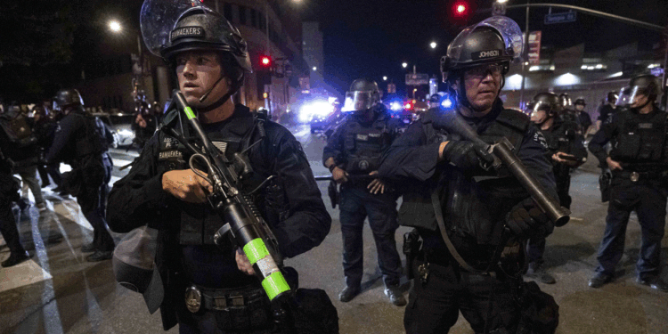 Police in riot gear stand guard.