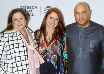 Abigail Disney, Jodie Evans and Neville Roy Singham stand in front of a "Tribeca Film Festival" backdrop.