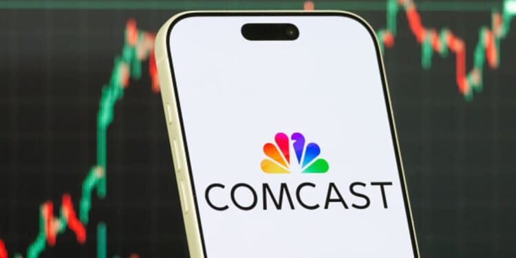 The Comcast logo is displayed on a phone while a stock market depiction is pictured behind.