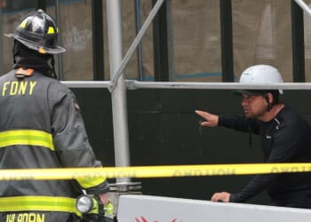 An FDNY member speaks to a member of the public near a construction site at the former Pfizer headquarters building in New York City on July 7, 2026.