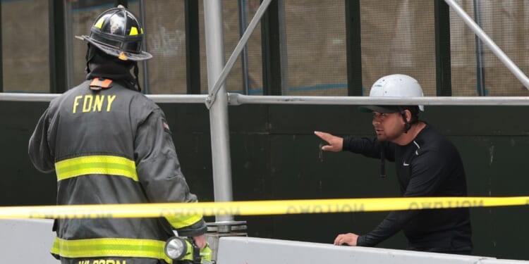 An FDNY member speaks to a member of the public near a construction site at the former Pfizer headquarters building in New York City on July 7, 2026.
